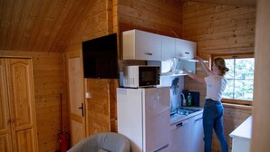 Une cuisine compacte avec des murs en bois, un four à micro-ondes encastré et un réfrigérateur.