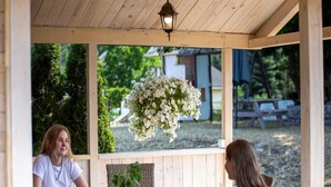 Une pergola en bois agrémentée de jardinières suspendues, une table et un banc.