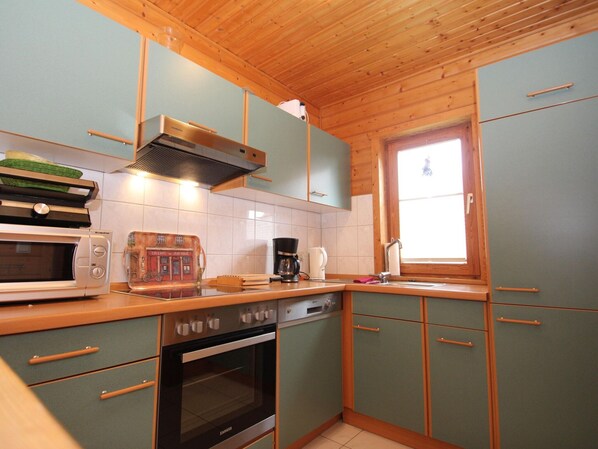 A compact kitchen with wooden cabinets, a built-in oven, a microwave, and a coffee maker. - Doppelhaushalfte in Hasselfelde (Oberharz am Brocken)