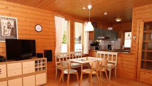 A wooden cabin interior with a dining area, kitchen, and a television on the left. - Doppelhaushalfte in Hasselfelde (Oberharz am Brocken)