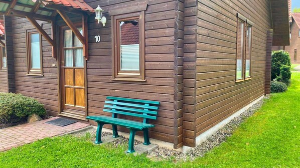 A wooden house with a number '10' on the wall, a wooden door, and a bench in front. - Doppelhaushalfte in Hasselfelde (Oberharz am Brocken)