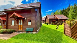 A wooden cabin with a red roof, a bench, and a well-maintained lawn. - Doppelhaushalfte in Hasselfelde (Oberharz am Brocken)
