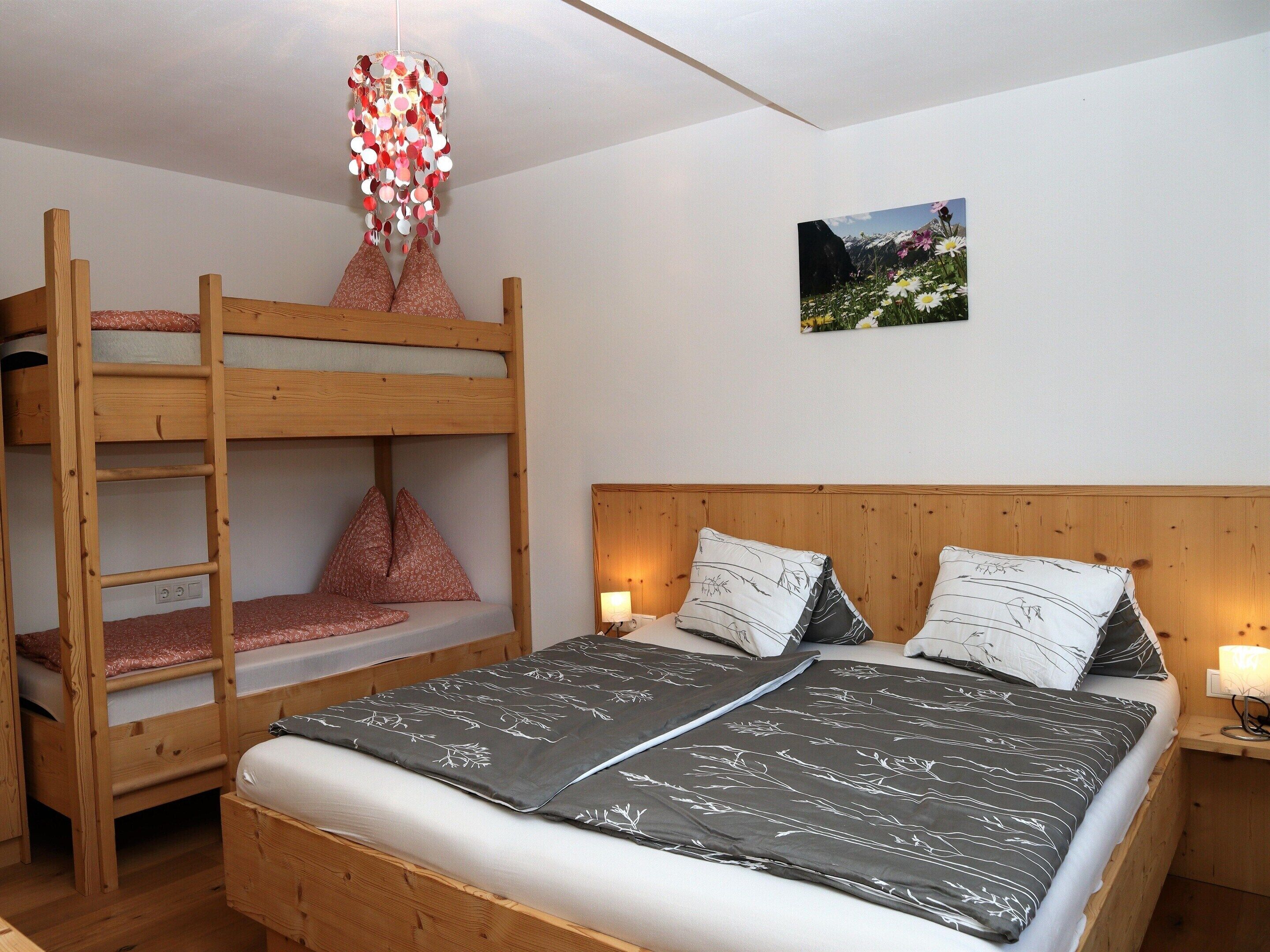 A bunk bed with a wooden headboard, a bedside table with a lamp, and a framed picture on the wall.