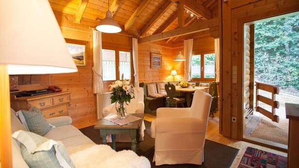 L’intérieur chaleureux d’un chalet en bois comprend un canapé, des fauteuils, une table à manger et offre une vue sur l’extérieur.