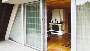 A room with a sliding glass door, a fireplace, and a wooden floor. - Holiday Home in Kashubia Near Lake (Suleczyno)