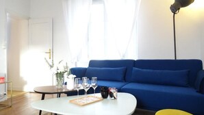 Ein Wohnzimmer mit einem blauen Sofa, einem weißen Couchtisch und einem gelben Hocker.