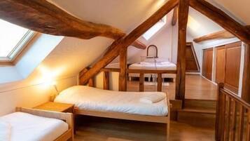 Un dormitorio acogedor en el ático, con vigas de madera, un tragaluz y una ventana pequeña.