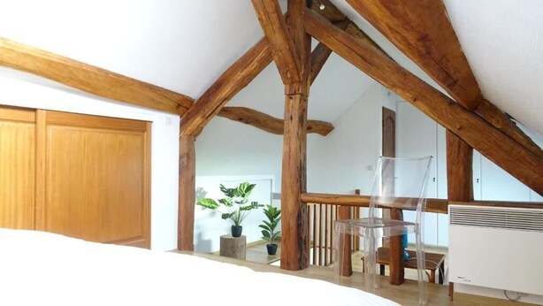 Ein Schlafzimmer mit freiliegenden Holzbalken, einem Bett, einem Schreibtisch und einer Heizung.