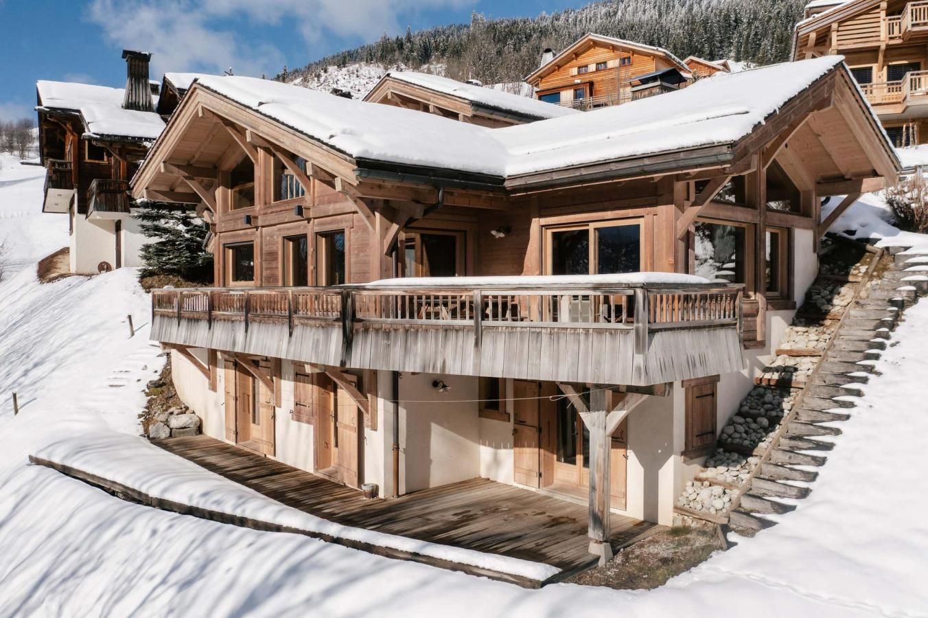 A multi-story wooden chalet with a balcony, surrounded by snow-covered terrain.