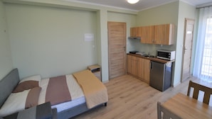 Ein kleines Zimmer mit Bett, einer Küchenzeile und einem Essbereich.
