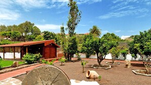 A courtyard with a stone fountain, potted plants, and a wooden building. - Villa With Pool and Beautiful Architecture (Ingenio)