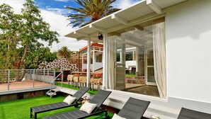 A modern villa with a glass-enclosed patio, outdoor seating, and a giraffe statue. - Villa With Pool and Beautiful Architecture (Ingenio)