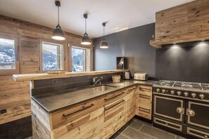 Eine moderne Küche mit Holzschränken, einer Edelstahlspüle und einem Gasherd.