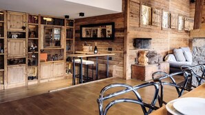 A rustic interior with wooden walls, a fireplace, a bar area, and a cozy seating arrangement.