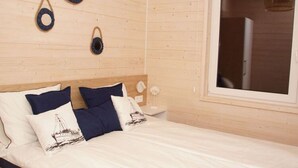 A bed with a white and navy bedding, a wooden headboard, and a window with a view. - Air-conditioned Holiday Homes, 2 Bedrooms (Mielno)