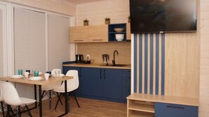 A modern kitchen with a dining area, featuring a wooden table, white chairs, and a blue and white striped accent wall. - Air-conditioned Holiday Homes, 2 Bedrooms (Mielno)