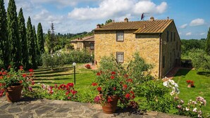 A stone house with a tiled roof, surrounded by a well-maintained garden with flowering plants. - Apartment in Montaione With Fireplace (Montaione)