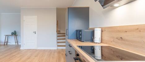 Een moderne keuken met houten kastjes, een magnetron en een inbouwoven.