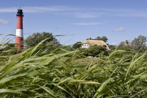 A lighthouse, a thatched-roof house, and surrounding greenery. - Ferienwohnung im Reetdachhaus auf der Pellworm (Pellworm)
