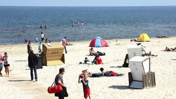 A beach with people sunbathing, a wooden deck, and a tent.