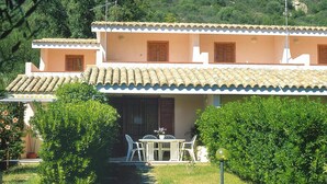 Un edificio a due piani con tetto in tegole, un balcone e un piccolo patio con tavolo e sedie.