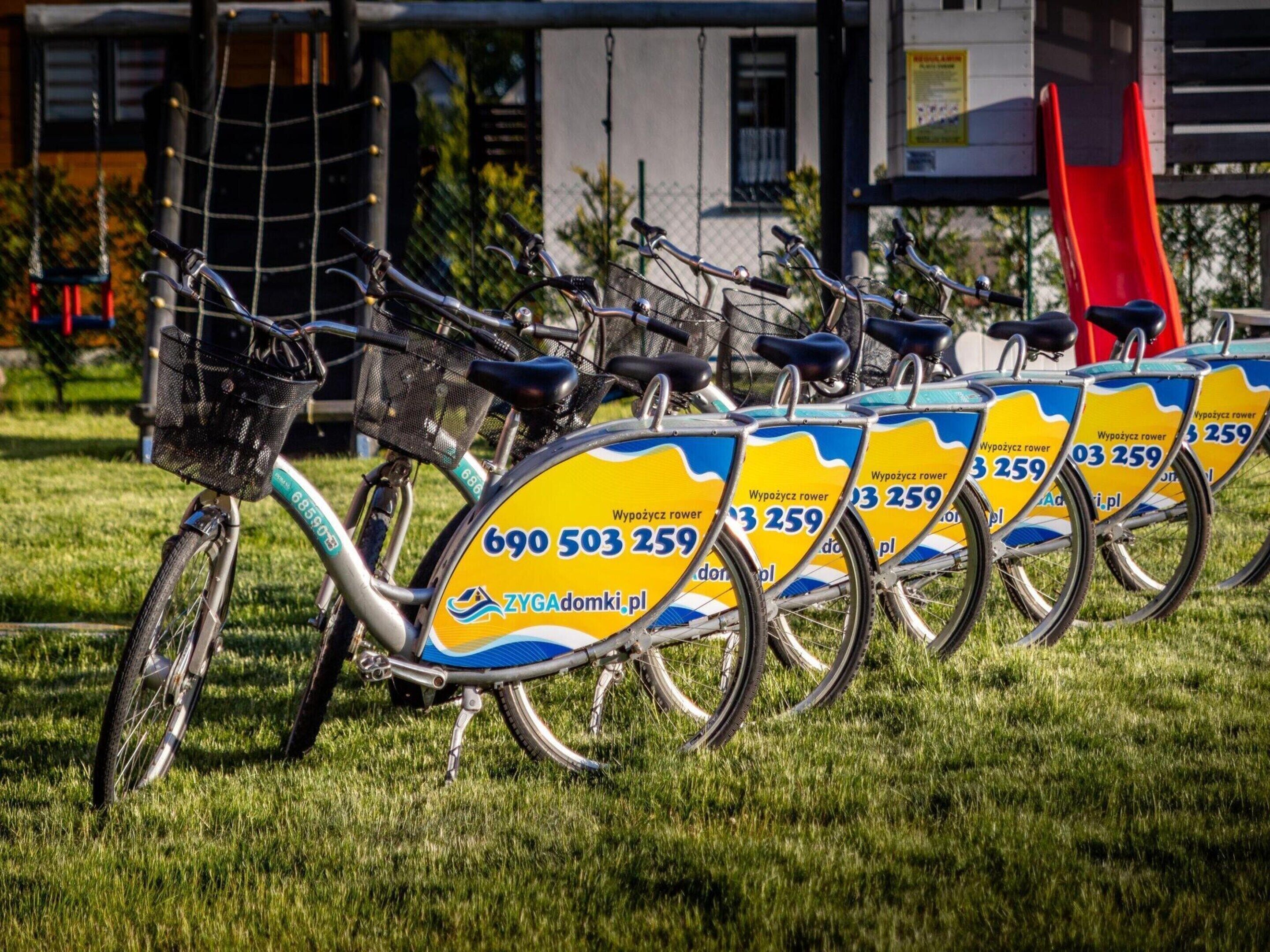 Une rangée de vélos aux couleurs jaune et bleu, garés sur l’herbe.