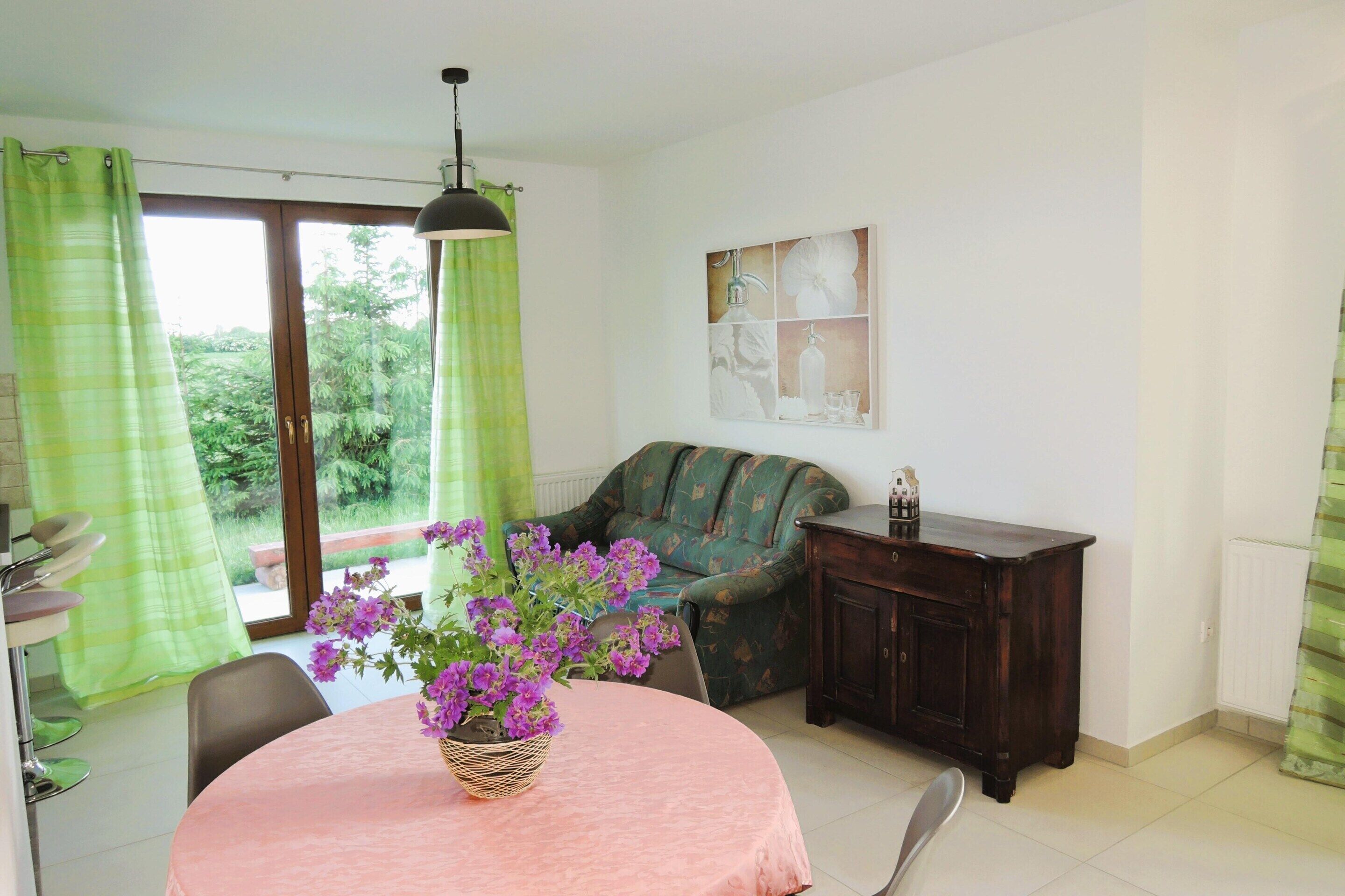 A room with a dining table, chairs, a sofa, a cabinet, and a window with curtains.
