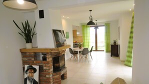 Una sala de estar con chimenea de ladrillo, un comedor y una cocina al fondo.