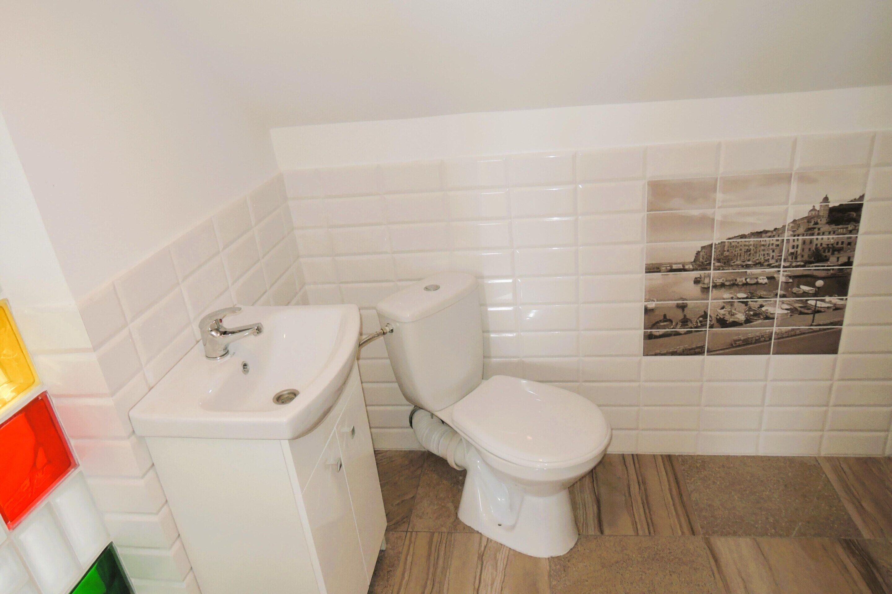 A bathroom with a toilet, sink, and tiled walls.