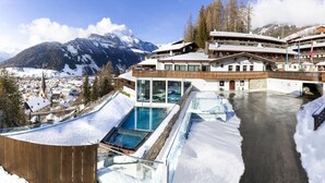 Un hôtel doté d’une piscine, entouré de paysages enneigés, avec des montagnes en toile de fond.