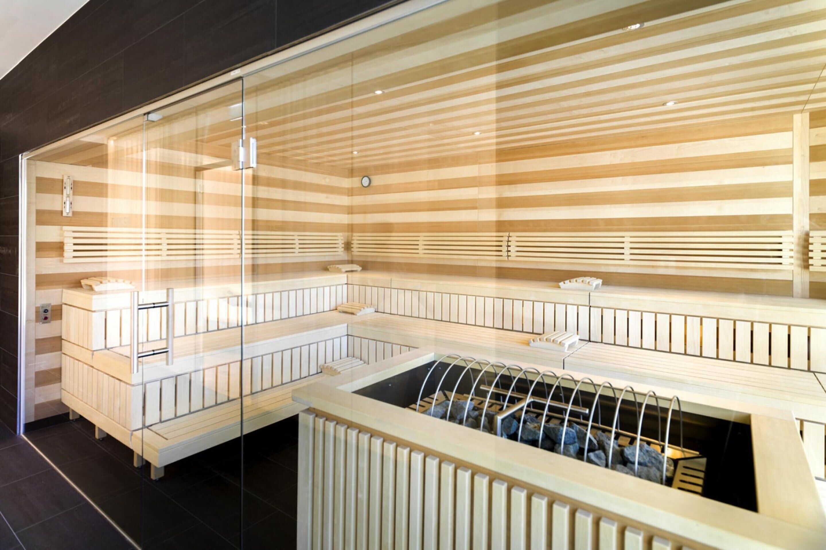Eine Sauna mit mehreren Bänken und einer Glasumrandung.