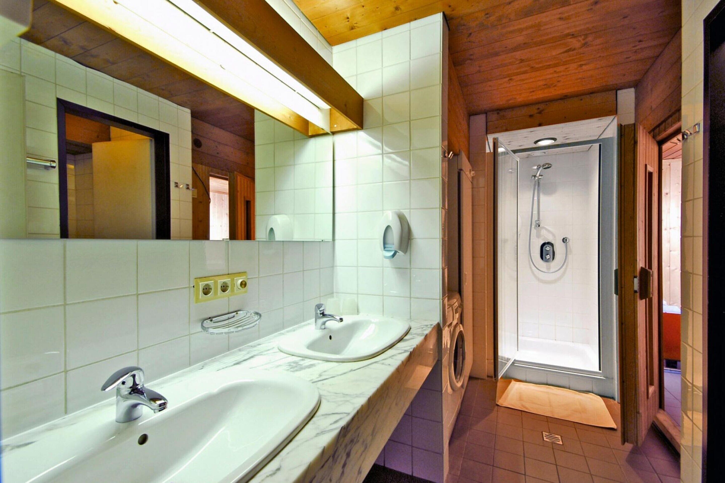 Une salle de bain avec deux lavabos, un miroir et une douche.