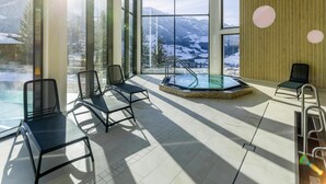 Un espace piscine intérieur moderne offrant une vue dégagée sur les montagnes enneigées grâce à de grandes fenêtres.