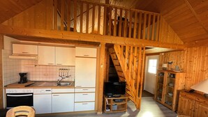 A rustic wooden interior with a kitchen, dining area, and a staircase leading to an upper level. - Holiday House at the Useriner See, Userin (Userin)