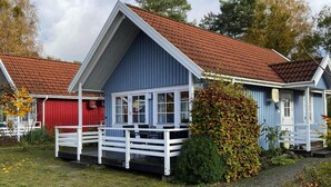 A blue building with a red roof, white porch, and a small garden area. - Holiday House at the Useriner See, Userin (Userin)