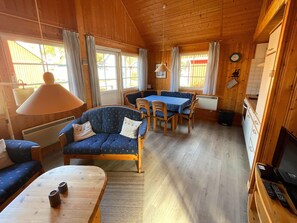 A cozy cabin interior with a dining area, a sofa, a coffee table, and a television. - Holiday House at the Useriner See, Userin (Userin)