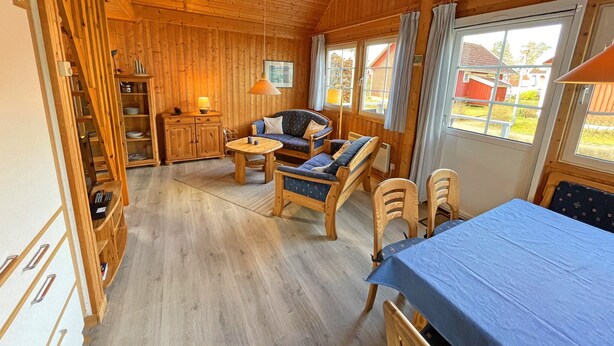 A wooden cabin interior with a sofa set, a dining table, and a bed. - Holiday House at the Useriner See, Userin (Userin)