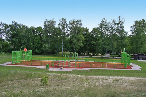 Une aire de jeux équipée de divers éléments, notamment un panier de basket, des structures d’escalade et une piste d’athlétisme.