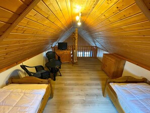 A cozy attic bedroom with two wooden beds, a small table, and a TV. - Holiday House at the Useriner See, Userin (Userin)