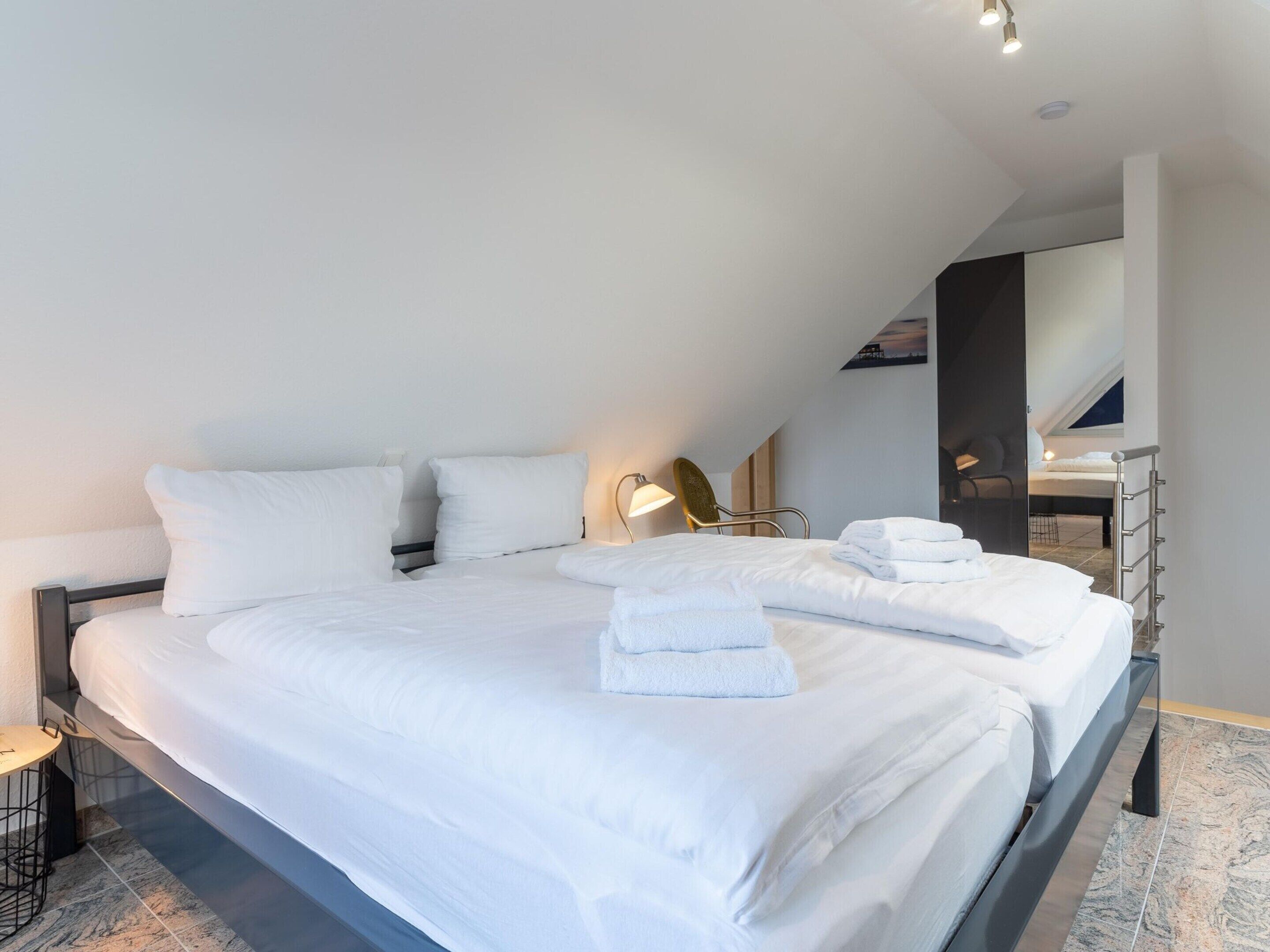 A modern hotel room with a large bed, a bedside table, and a chair.