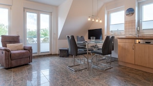 A modern kitchen with a dining area, a sofa, and a TV. - Wohnung in St. Peter Ording (St. Peter-Ording)