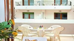 A dining area with a table set for two, white plastic chairs, and a balcony with a railing. - Holiday Flat Galeria Gran Mado in Caorle (Caorle)