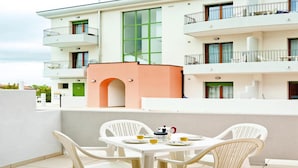 A modern apartment with a balcony, white furniture, and a view of neighboring buildings. - Holiday Flat Galeria Gran Mado in Caorle (Caorle)