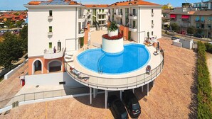 A hotel with a central swimming pool, multiple balconies, and a parking area. - Holiday Flat Galeria Gran Mado in Caorle (Caorle)