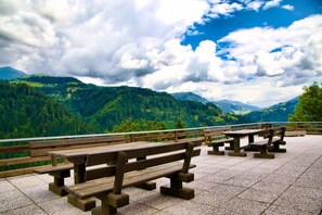 Un área de picnic con bancos y mesas, con vistas a un paisaje montañoso y cielo despejado.
