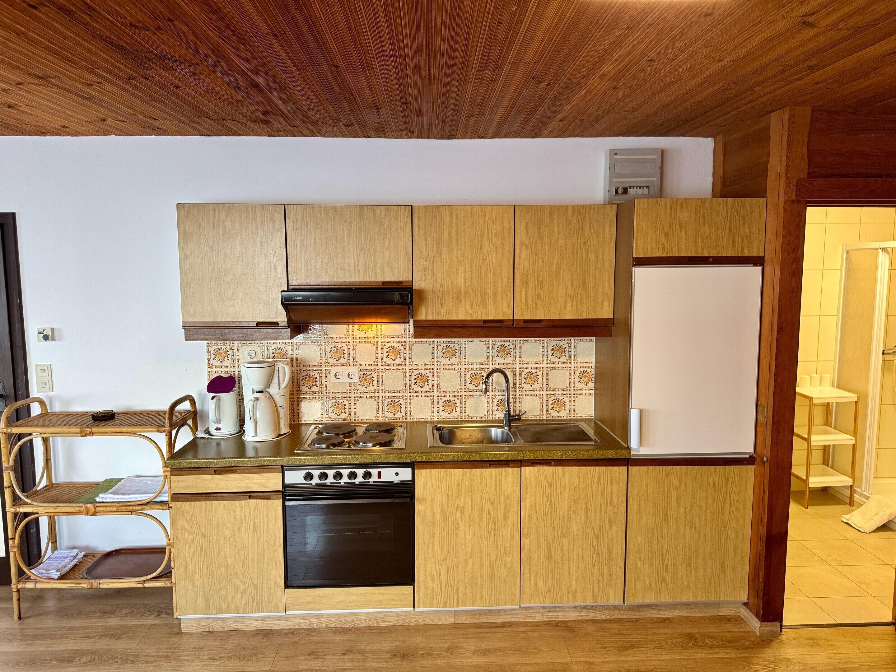 Eine kleine Küche mit Holdekor-Schränken, einem Backofen, einer Spüle und einer Kaffeemaschine.
