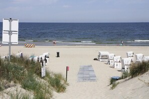 Una spiaggia con cabine numerate, un cartello segnaletico e una vista libera sull'oceano.