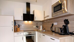 Eine moderne Küche mit weißen Schränken, Edelstahlgeräten und Holz Arbeitsplatten.