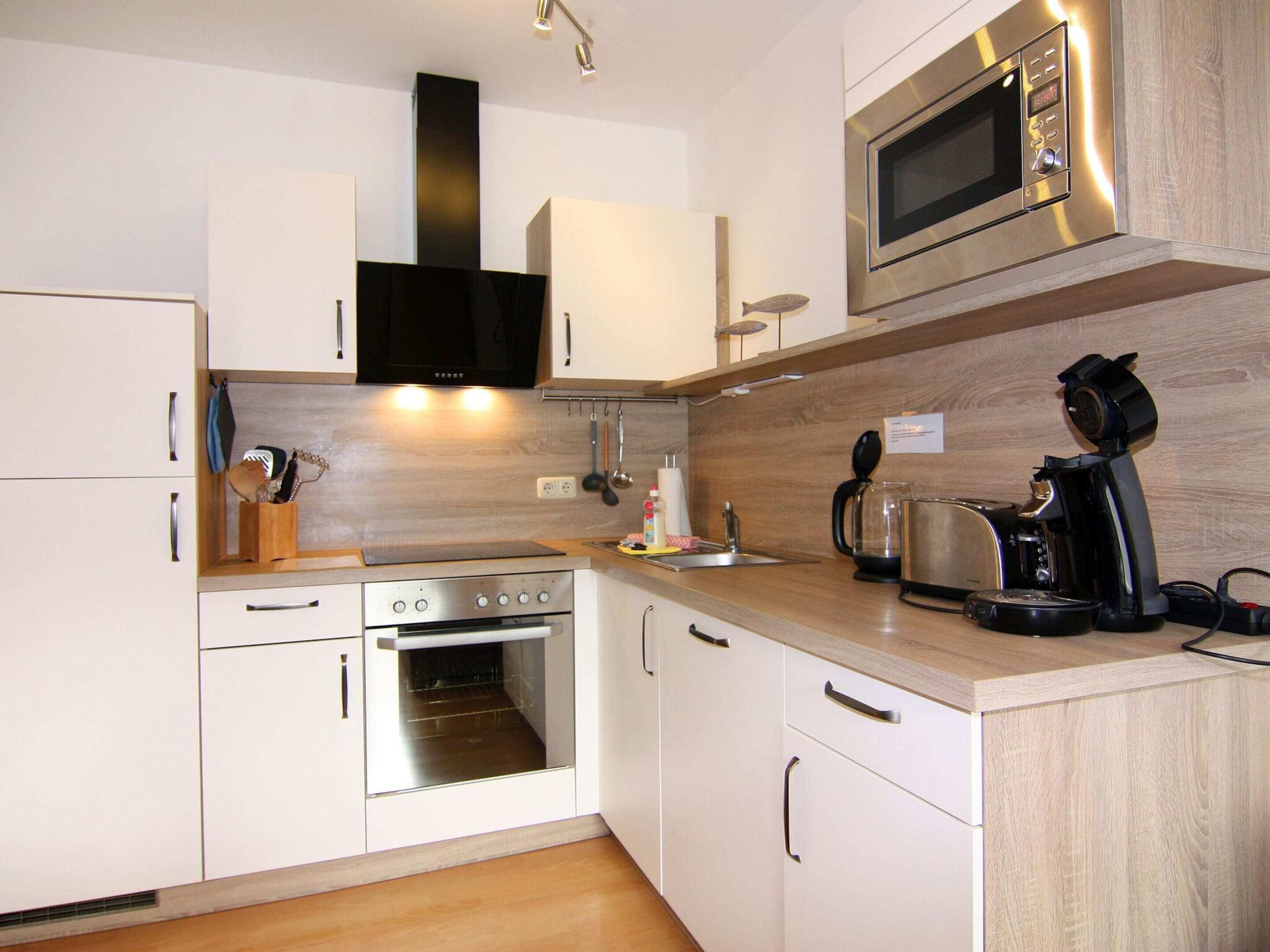 A modern kitchen with stainless steel appliances, wooden cabinets, and a built-in oven.