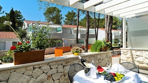 Eine Terrasse mit Steinmauer, Sitzgelegenheiten im Freien und einem Esstisch.